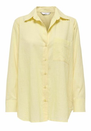 Svijetlo žuta košulja dugih rukava s gumbima, ovratnikom i lijevim džepom na prsima, prikazujući blago teksturiranu tkaninu.