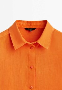 Kurzes, orangefarbenes Hemd mit Knöpfen. Hergestellt aus leichtem Stoff mit glatter Textur. Verfügt über einen klassischen Kragen und fünf Knöpfe an der Vorderseite.