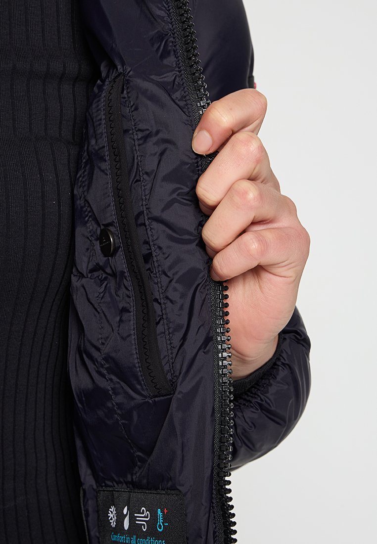 Schwarze Pufferjacke mit Innenfutter, Reißverschluss und Druckknopfverschluss; strukturierter Stoff; beinhaltet ein Etikett mit Symbolen für wetterfeste Eigenschaften.