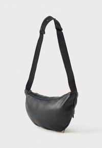 Saco de ombro de couro acolchoado preto com alça ajustável e fecho de zipper, exibido contra um fundo branco liso.