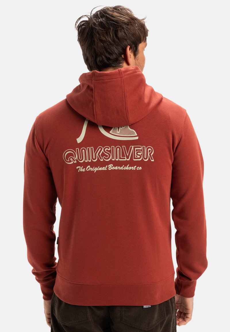 Sweat à capuche rouge avec un grand logo graphique blanc au dos, présentant une capuche à cordon de serrage et des poignets côtelés. Texture douce, design décontracté.