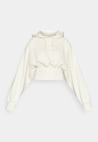 Kuttet hettegenser i myk hvit stoff med lange, voluminøse ermer og hette med snor. Har en tilpasset, rynket midje.