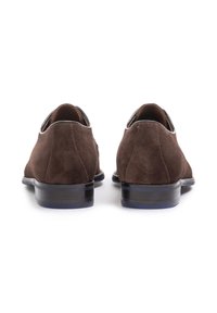 Scarpe in suede marrone con finitura liscia, punta tonda e tacco basso impilato. Presentano dettagli in pelle nera lungo il collo.
