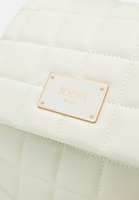 Sac à dos matelassé en cuir synthétique. Doté d'une plaque dorée avec "JOOP! JEANS" et de détails de couture visibles.