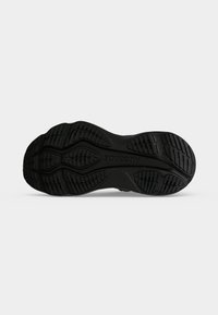 Semelle de chaussure en caoutchouc noire avec motifs de bande de roulement texturés et le nom de la marque Saucony embossé au centre.