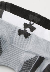 Három pár zokni fekete, fehér és szürke színben, textúrázott anyaggal, bordás szegéllyel és logó mintázattal az oldalán.