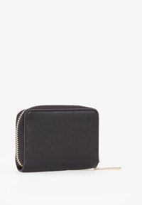 Portafoglio in pelle nera con forma strutturata, dettagli in cerniera dorata e design minimalista. Presenta una piccola linguetta in metallo.