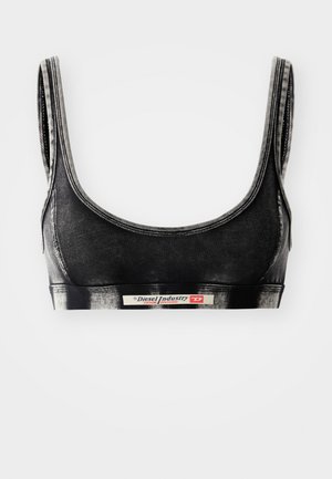 Bralette nera con scollatura a barca, realizzata in un materiale morbido. Presenta un'ampia banda elastica con logo e cuciture a contrasto.