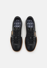 Scarpe da ginnastica nere realizzate in pelle e camoscio, con lacci, una soletta decorata e una suola in gomma con un accento marrone.