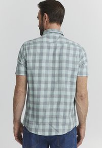 Camicia a maniche corte, verde menta e grigia a quadri con orlo dritto e colletto, realizzata in tessuto leggero, mostrata di spalle.