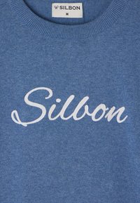 Sudadera azul hecha de un tejido suave. Presenta el logo en cursiva "Silbon" en blanco en la parte frontal. Cuello redondo y detalle de ribete en el dobladillo. Etiqueta de tamaño M visible.
