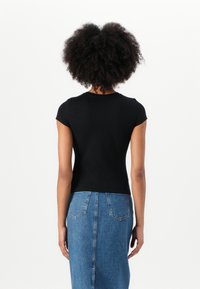 T-shirt nera aderente con maniche corte e scollatura rotonda, abbinata a una gonna in denim azzurro chiaro con tasche applicate e taglio dritto.