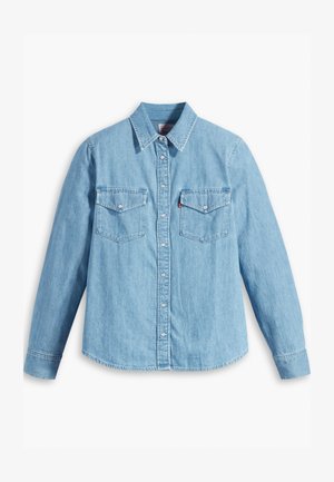 Lyseblå denimskjorte med lange ærmer, spidse krave, to brystlommer, knaplukning og subtil tekstur. Ingen synlige mønstre.