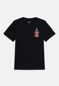 T-shirt en coton noir avec un design graphique rouge et argent mettant en avant des boîtes empilées et un logo Jumpman sur le côté supérieur gauche.