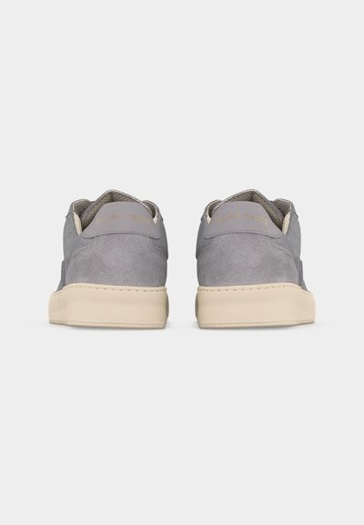 Paire de baskets en daim gris avec semelles beige, vues de dos, arborant la marque "FILLING PIECES" sur les languettes de talon.