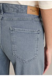 Lichtblauwe denim jeans met een achterzak voorzien van een gestikt ontwerp en een tan lederen patch met het label "Marc O'Polo" op de tailleband.