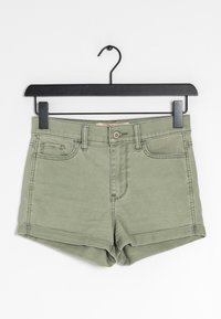 Olivově zelené džíny kraťasy s klasickým designem pěti kapes, zapínáním na knoflíky a ohrnutým lemem; zavěšené na černém plastovém ramínku.