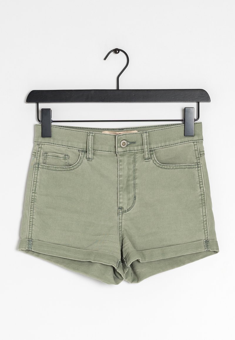 Olivově zelené džíny kraťasy s klasickým designem pěti kapes, zapínáním na knoflíky a ohrnutým lemem; zavěšené na černém plastovém ramínku.