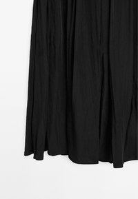 Schwarzes Midikleid mit einem lockeren Design, das aus einem leichten, strukturierten Stoff besteht und einen unregelmäßigen Saum aufweist, wodurch ein entspannter Look entsteht.