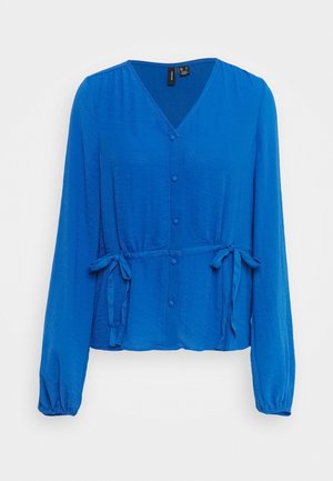 Blouse bleue à manches longues avec col en V, boutons sur le devant, poignets élastiqués froncés et liens latéraux ajustables créant un effet taille cintrée.