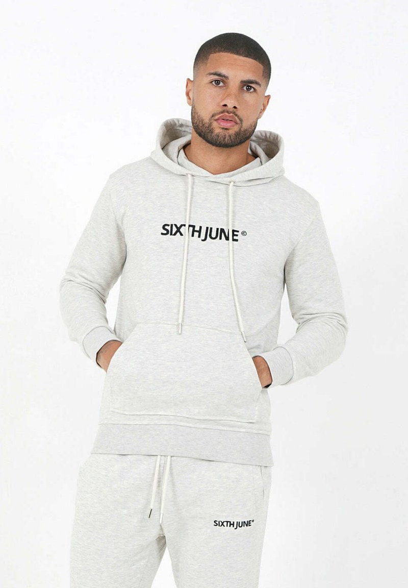 Sudadera ligera gris claro hecha de una tela suave, con un bolsillo frontal, cordones y un logo negro "SIXTH JUNE" en el pecho.