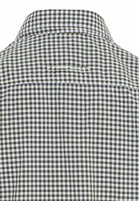 Achteraanzicht van een zwart-witte klein geruite shirtkraag met een gestikte stoffenlusdetail.