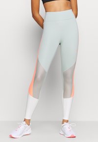 Leggings de color azul claro con acentos en coral y paneles de malla. El diseño de cintura alta presenta una textura suave y una forma ajustada, adecuada para ropa deportiva.