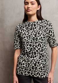Tričko s leopardím potiskem v šedé barvě s černými skvrnami, krátkými rukávy a kulatým výstřihem. Měkký materiál s volným střihem.