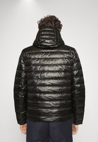 Polstret sort jakke med en blank overflade, der har hætte og vandret quiltet mønster på ryggen.