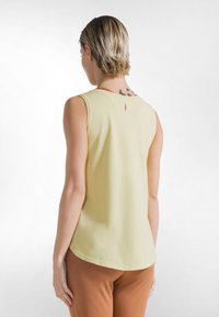 Top amarillo sin mangas hecho de tela suave, con un escote redondo y una pequeña etiqueta en la parte trasera. Textura lisa, dobladillo ligeramente curvado.