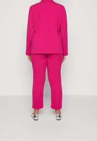 Fuchsiaset bestående av en skräddarsydd kavaj och matchande byxor, mjuk tyg, långa ärmar och metallic silver skor.