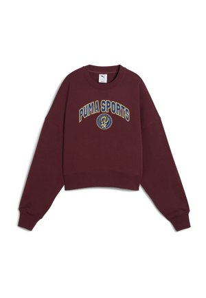 Burgundy kort hoodie gjord av mjukt tyg, med rund halsringning, sänkta axlar och grafiken "PUMA SPORTS" i gult och blått.