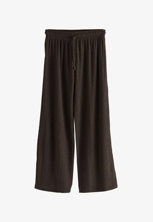 Plati kelnės tamsiai rudos tekstūruotos medžiagos. Yra elastinga juosmens juosta su raišteliu, leidžiančiu reguliuoti prigludimą.