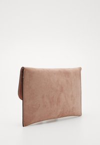 Prostokątna różowa torebka kopertowa zamszowa z zapięciem na klapę, pokazana stojąca na białej powierzchni.