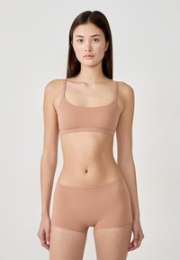 Bralette color marrone chiaro con spalline sottili, abbinato a boxer coordinati. Texture liscia, design senza cuciture, bande elastiche in vita su entrambi i capi.