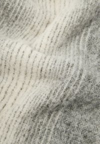 Vilnas audums ar mīkstu, teksturētu virsmu baltā un pelēkā krāsā, ar viegli manāmiem horizontāliem svītrainiem un nedaudz pūkainu izskatu.