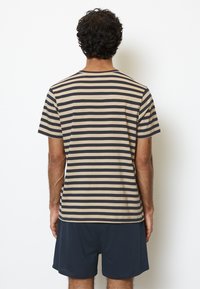 Herrkortärmad T-shirt i beige och marinblå ränder, med rund halsringning och mjukt bomullstyg. Bärs med matchande mörka shorts.