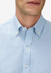 Ljusblå knapp-up skjorta med krage, som har en texturerad tyg, vita knappar och en klassisk passform.