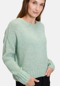 Ljusgrön stickad tröja med lös passform, ribbad fåll och mudd, samt en strukturerad design. Har rund halsringning och vida ärmar.