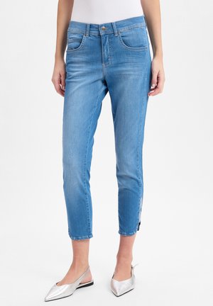 Helle blaue Denim-Jeans mit schlankem Schnitt, knöchelbürtig geschnitten, mit seitlichen Reißverschlüssen und klassischem Fünf-Taschen-Design. Glatte Textur.