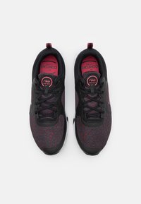 Sneakers Nike Comfort con tomaia a maglia nera e rossa, lacci neri, logo rotondo sulla linguetta e suola bianca.