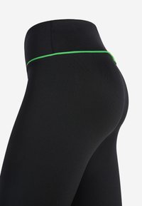 Leggings neri a vita alta con una linea di accentuazione verde in vita, realizzati in un tessuto morbido ed elastico; il design aderente si adatta al corpo.