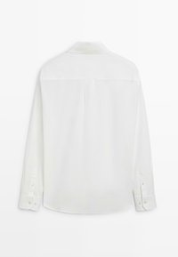 Camicia bianca a maniche lunghe in tessuto liscio, con colletto e polsini con bottoni. Sul retro presenta un design semplice senza motivi.