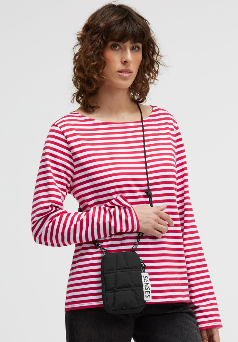 Red and white striped long-sleeve shirt with a round neckline, paired with a small black quilted crossbody bag featuring a label.