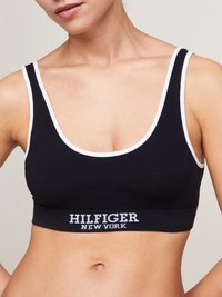Bralette nera a coste con bordo bianco e fascia elastica, con logo testuale "HILFIGER NEW YORK", progettato per comfort e supporto.