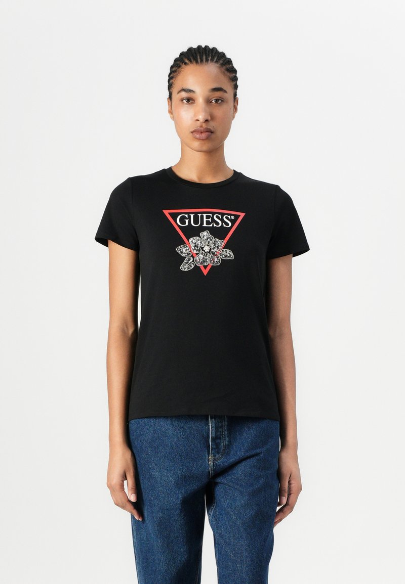 Svart bomull T-skjorte med en rød trekantet logo som har "GUESS"-tekst og blomstergrafikk. Korte ermer og klassisk passform.