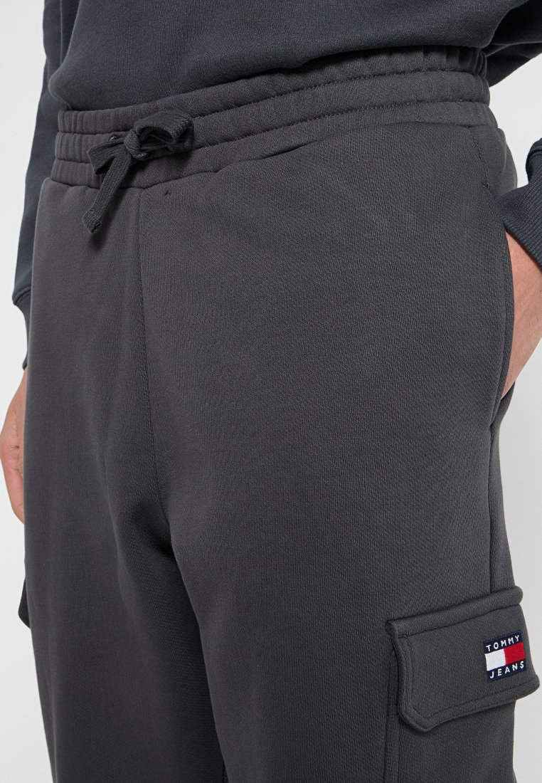 Mörkgrå sweatpants med dragsko i midjan, sidofickor och en Tommy Jeans-logotyppatch på fickan på höger lår.