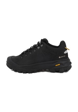 Μαύρο παπούτσι πεζοπορίας με παχιά σόλα Vibram, αδιάβροχη ετικέτα Gore-Tex, μεταλλικές ραφές και επενδεδυμένο γιακά σε λευκό φόντο.