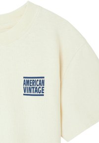 T-shirt en coton crème à manches courtes et col rond. Présente un logo imprimé bleu "AMERICAN VINTAGE" sur la zone de la poitrine gauche.