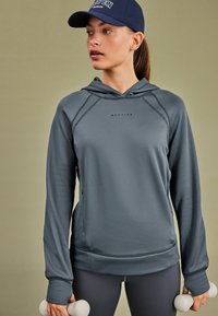 Hallukas halli kapuutsiga sweatshirt, mis on valmistatud siledast kangast, rinnal logoga, küljetaskudega ja varrukates pöidlaugudega.